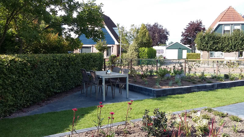 Afgewerkte achtertuin met bestrating, gazon en border